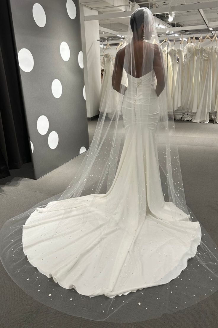 a woman in a wedding dress looking at her veil