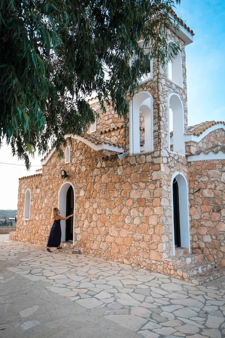 a woman is standing in the doorway of a stone building with white trim and arched windows