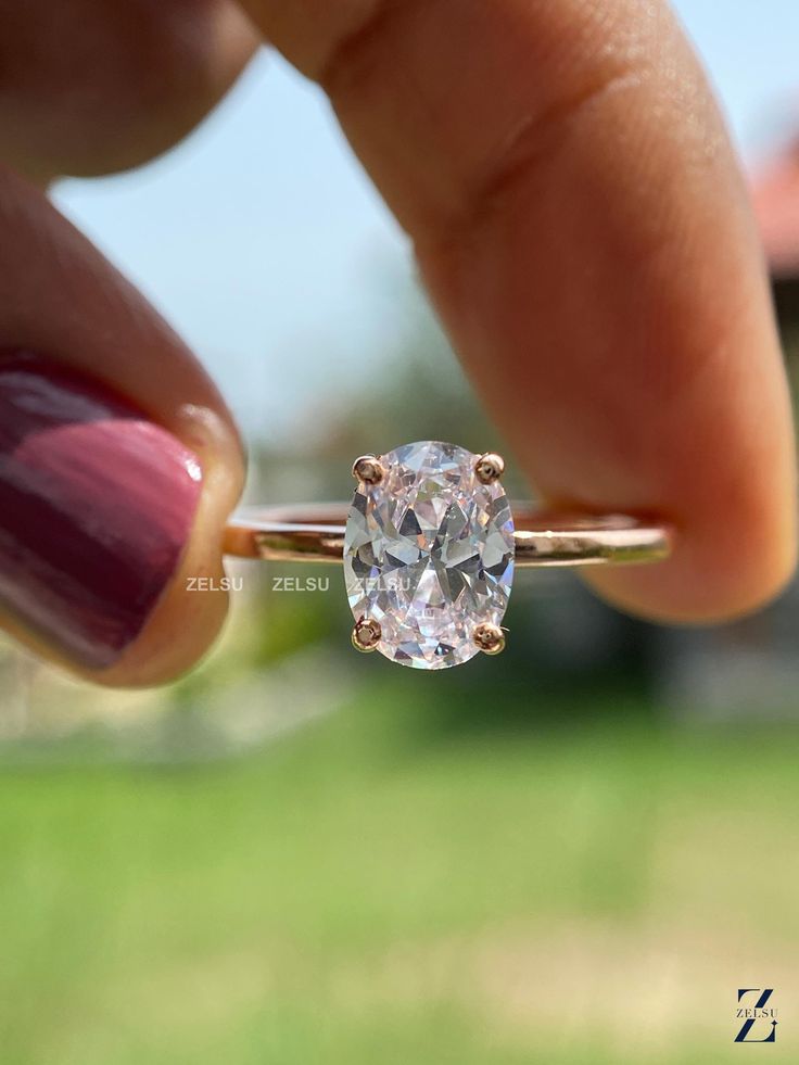 a close up of a person's hand holding a ring with a diamond in it