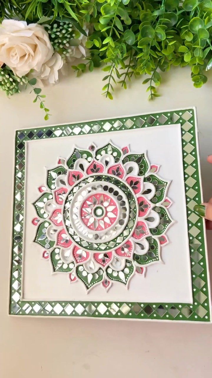 a handmade card with an intricate flower design on the front and side, surrounded by greenery