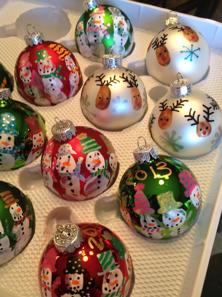 twelve christmas baubles are sitting on a white tray with snowmen and reindeers