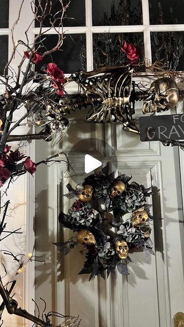 a halloween wreath on the front door of a house with skulls and flowers hanging from it