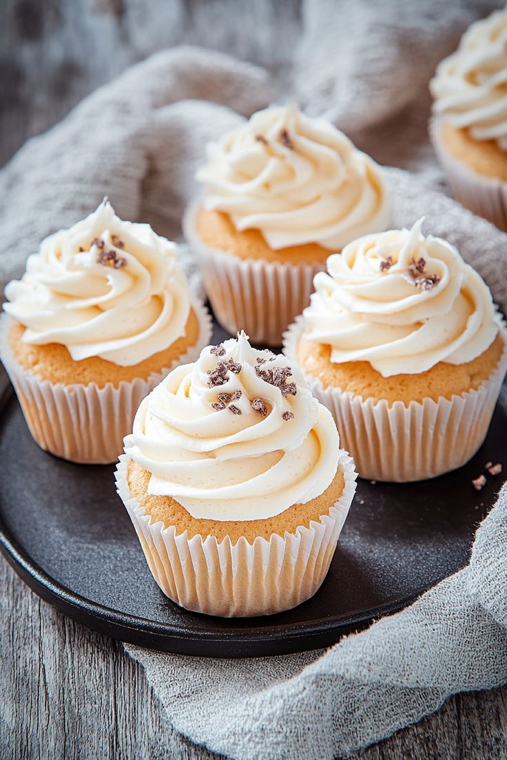 cupcakes with white frosting and sprinkles on a black plate