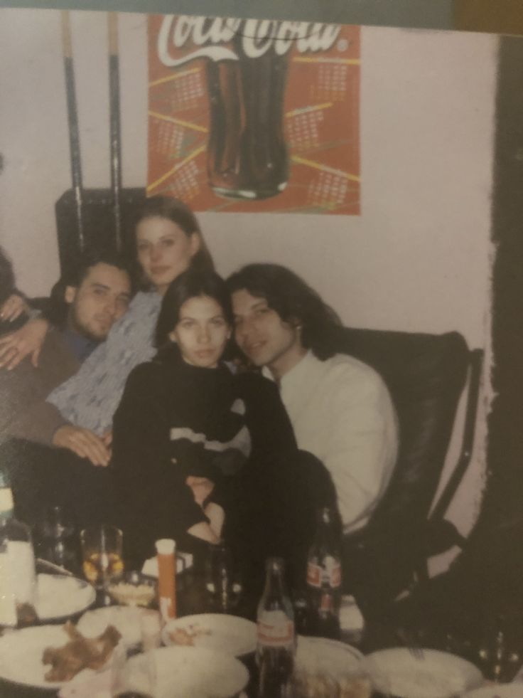 a group of people sitting around a table with food and drinks on top of it