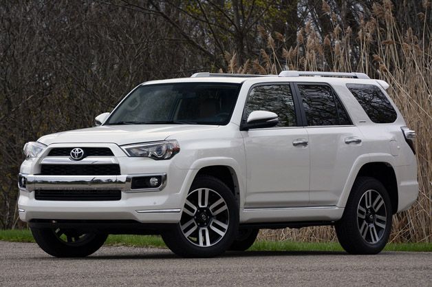 a white toyota 4runner parked on the side of the road in front of some trees