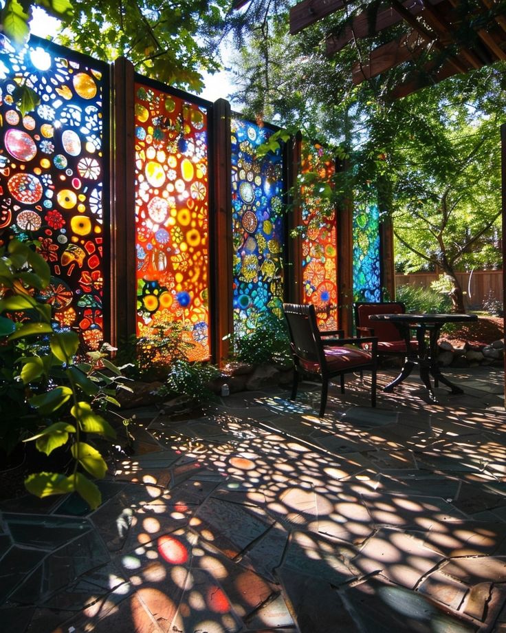 an outdoor area with several colorful glass panels on the wall and chairs in the sun