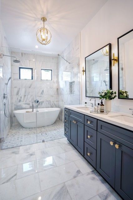 a bathroom with two sinks and a bathtub in the middle, along with a large mirror on the wall