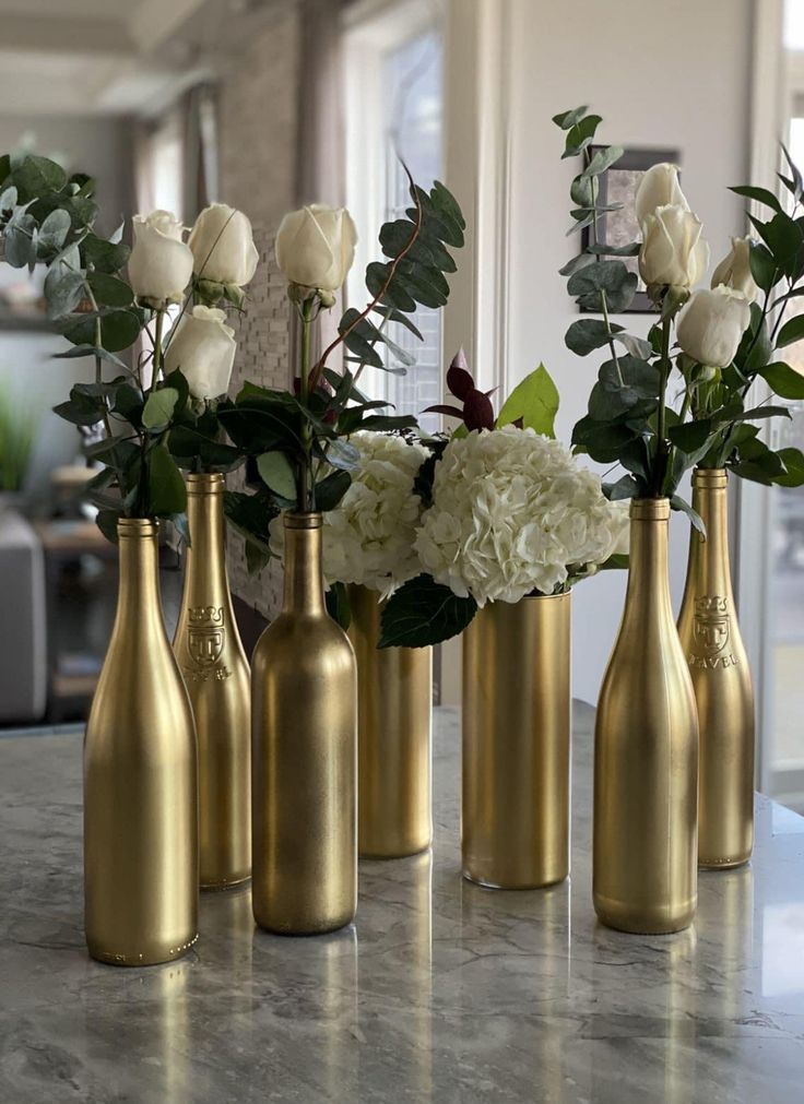 four gold vases with white flowers in them