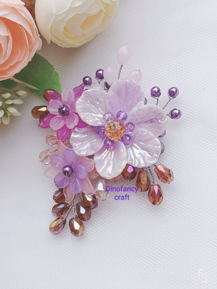 two flowers are sitting next to each other on a white surface with pink and purple beads