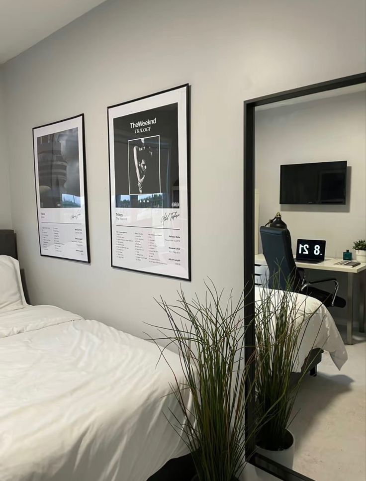 a bed sitting under two framed pictures next to a desk with a computer on it