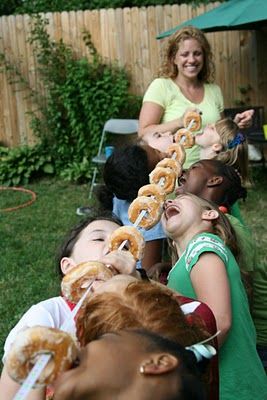 a group of children eating donuts in the back yard with their mother and grandmother