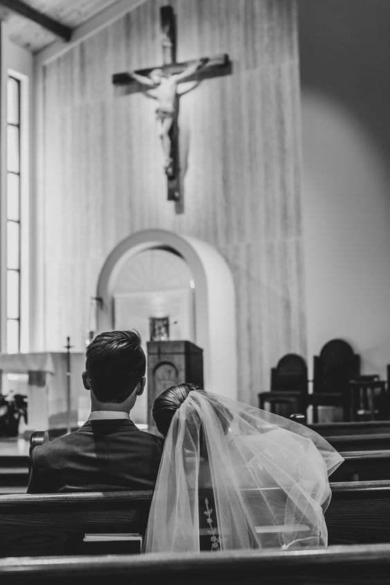 a bride and groom sitting in front of the alter at a church during their wedding ceremony