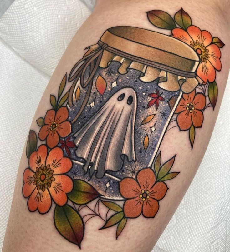 a woman's thigh with flowers and a ghost in a jar tattoo on it