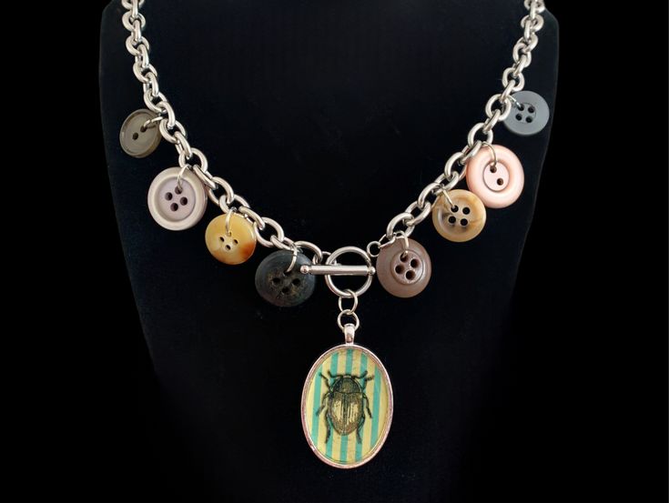 a necklace that has buttons on it and a button charm hanging from the clasps