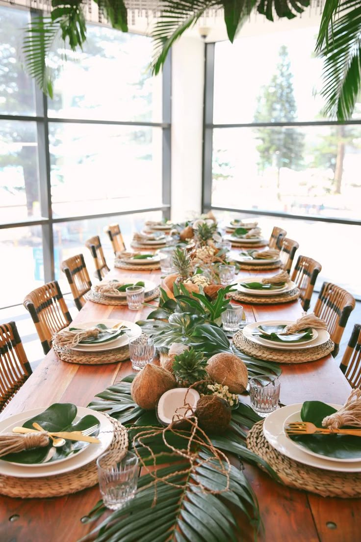 the table is set with plates and place settings for an elegant tropical - themed dinner