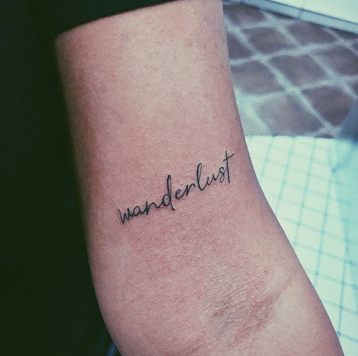 a woman's arm with the word wanderlust tattooed on it