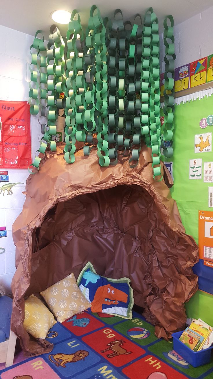 an indoor play area with toys and decorations on the walls, including a cave made out of cardboard