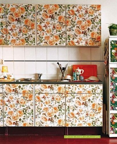 an image of a kitchen setting with flowers on the wall and cupboards behind it