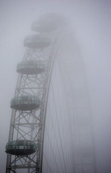 a ferris wheel in the fog on a cloudy day