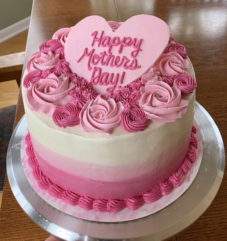 a heart shaped cake with pink frosting and roses on the bottom is sitting on a table