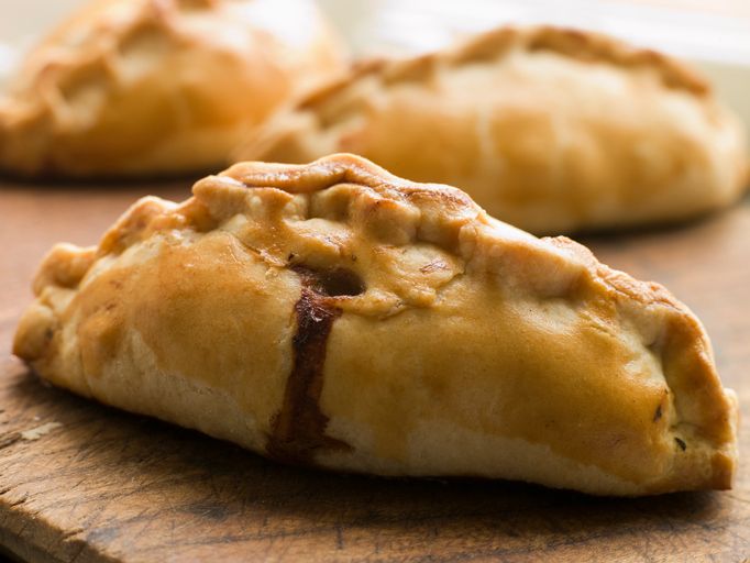 three pastries sitting on top of a wooden cutting board