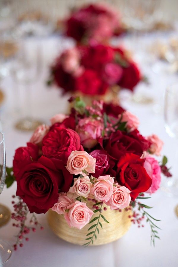 a vase filled with lots of red and pink flowers on top of a white table