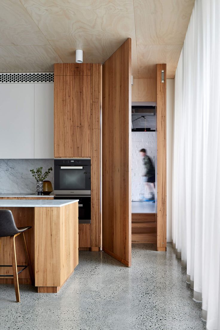 an open kitchen with wooden cabinets and white curtains