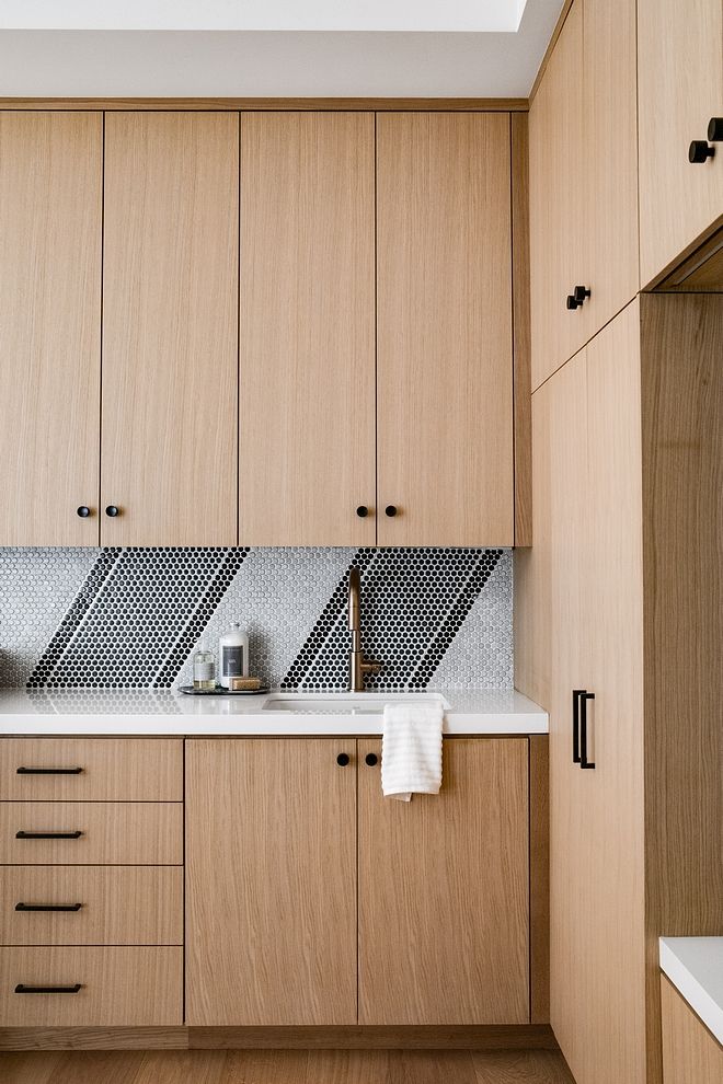 a kitchen with wooden cabinets and white counter tops, along with black accents on the backsplash