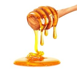 honey dripping from wooden spoon on white background