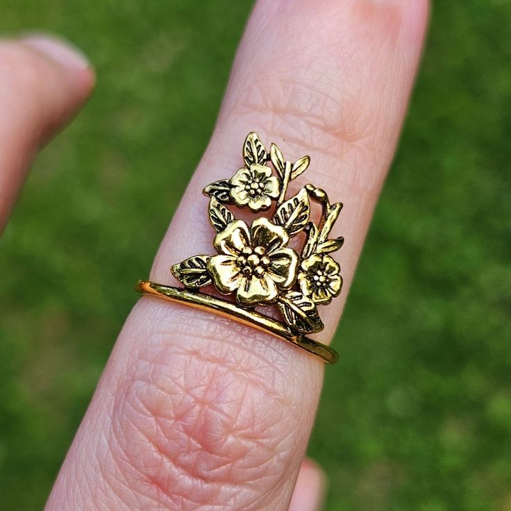 a close up of a person's hand wearing a ring with flowers on it