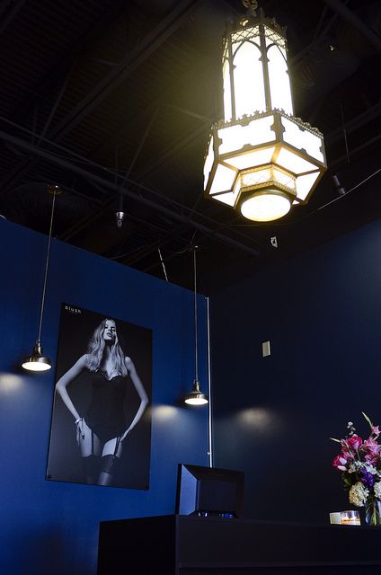 a chandelier hanging from the ceiling above a desk with a vase of flowers on it