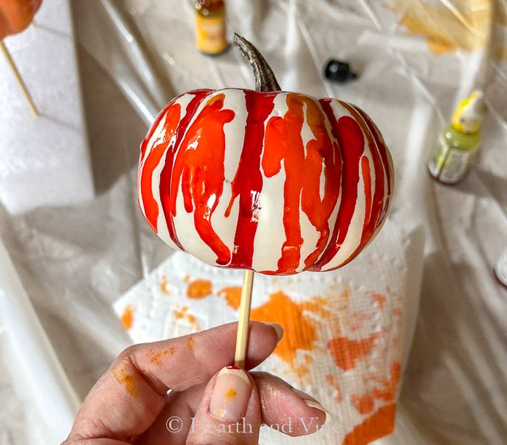 a hand holding a candy lollipop with red and white swirls on it