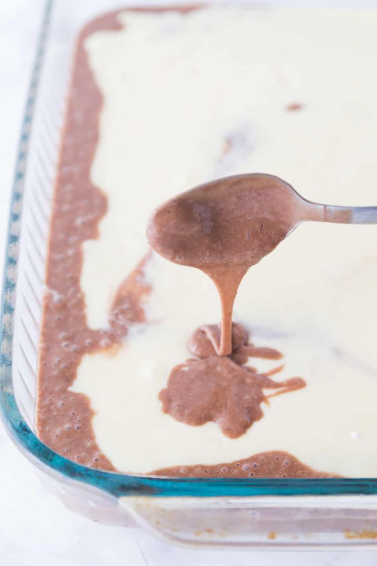 a spoon is being used to dip some food into the batter in a glass dish