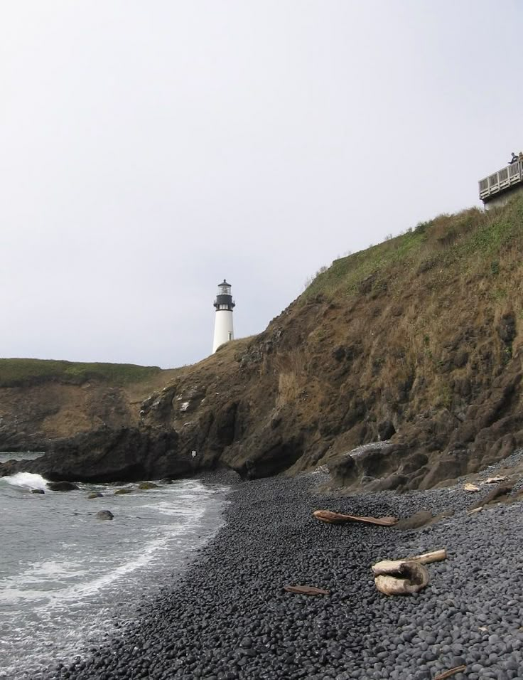 a light house on top of a hill next to the ocean