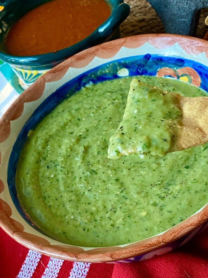 a bowl filled with guacamole and tortilla chips on top of a table