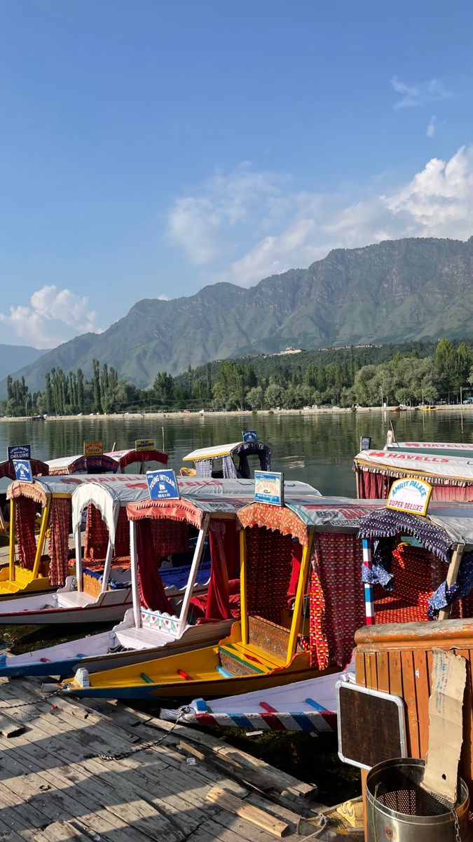 there are many boats that are docked on the water and mountains in the back ground