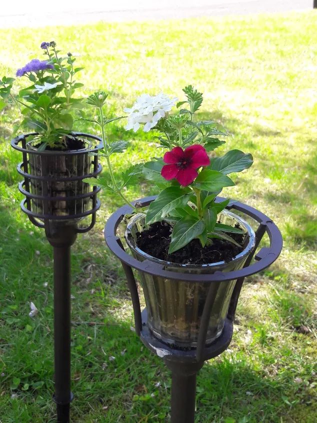 two metal planters with flowers in them on the grass