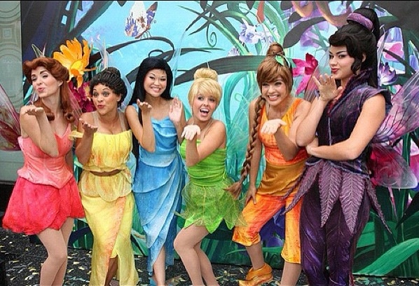 the girls are dressed up as tinkerbells in front of a wall painted with flowers