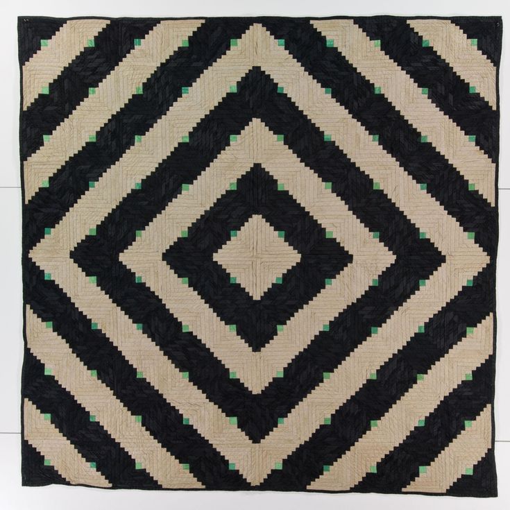 a black and white quilt with green squares on the bottom, in front of a white background