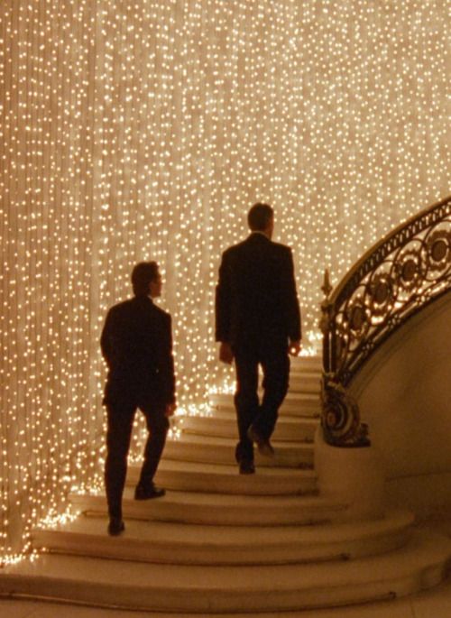 two men walking up some stairs covered in lights