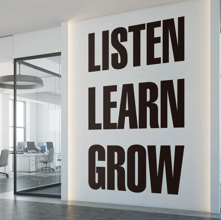 the words listen, learn, grow are displayed on a wall in an office setting