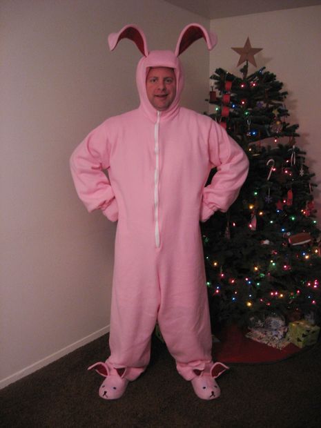 a man in a pink bunny costume standing next to a christmas tree