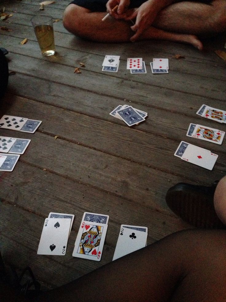 people sitting around playing cards on a wooden table