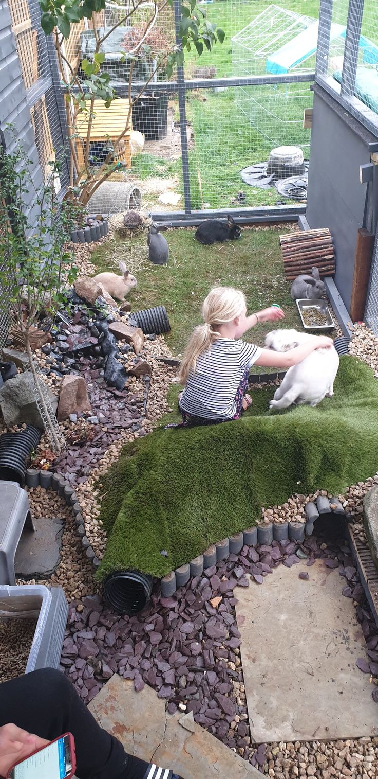 a woman sitting on top of a green grass covered ground next to a white dog