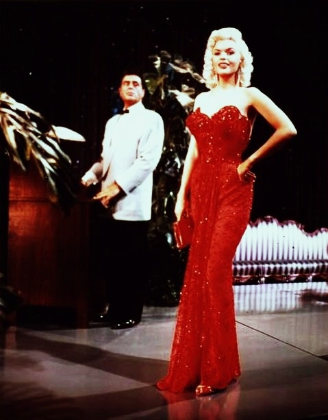 a man standing next to a woman in a red dress