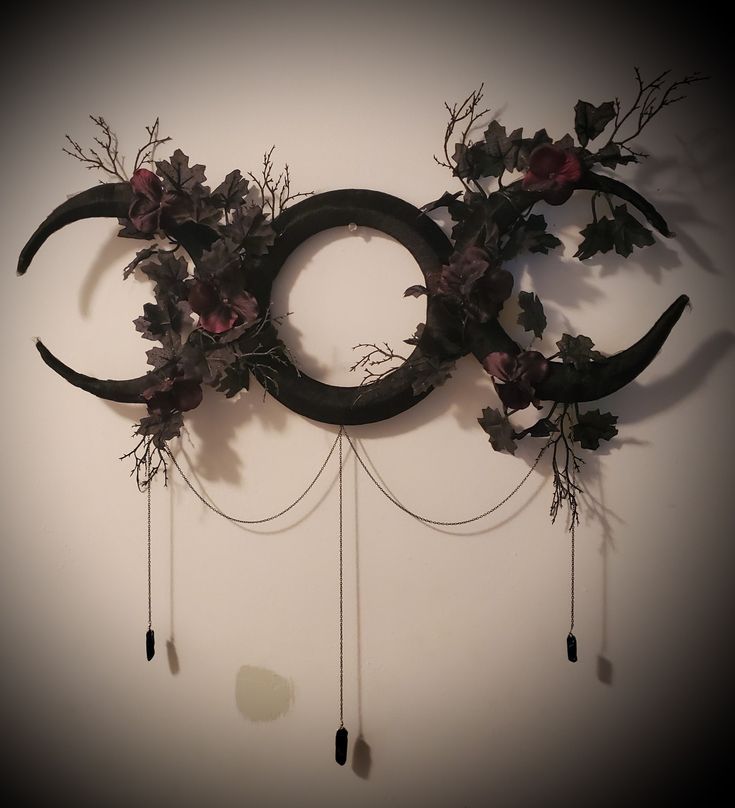 a wall hanging made out of branches and flowers with the moon in the middle on it