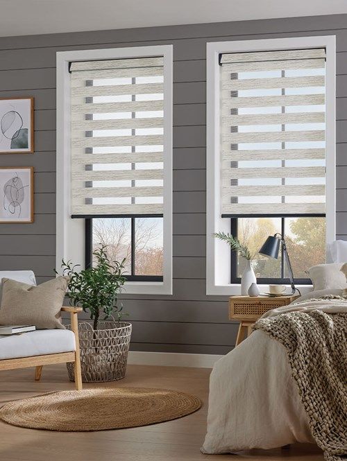 a living room with grey walls and two windows that have blinds covering them in shades