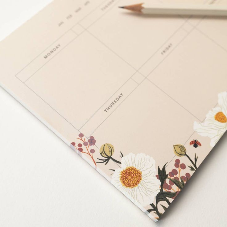 a notepad with flowers on it next to a pencil