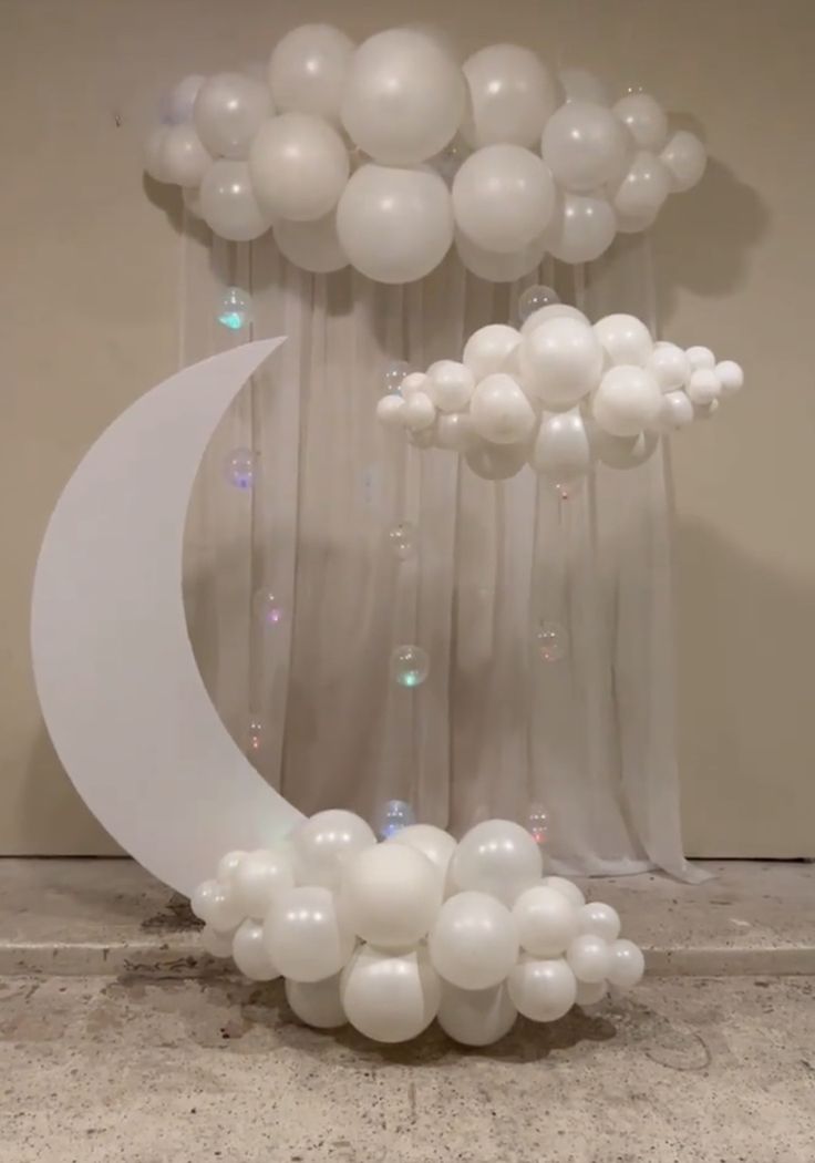 balloons are floating in the air near a crescent moon and curtain with lights on it