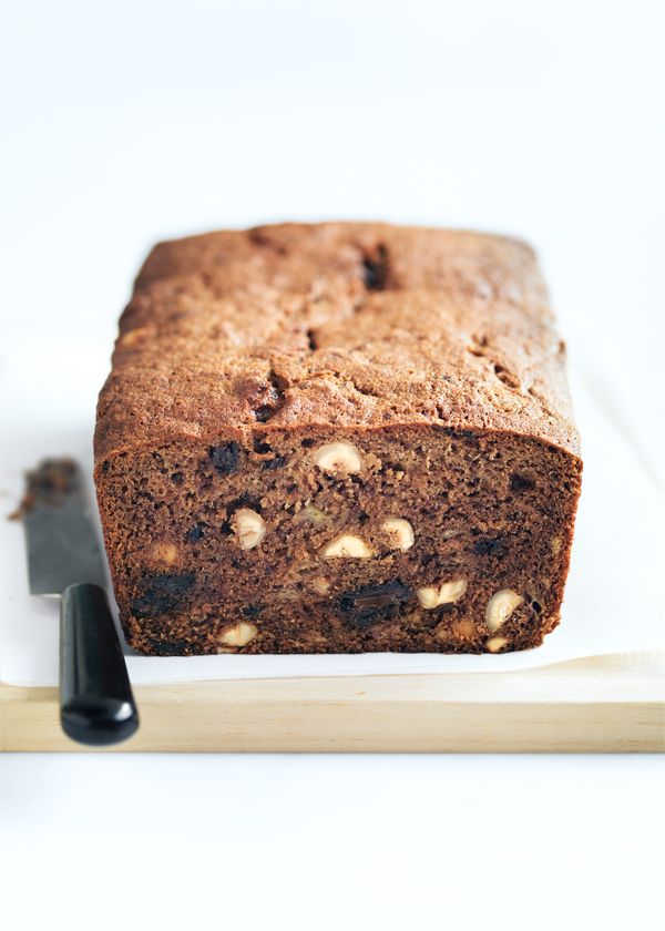 a loaf of chocolate chip banana bread on a cutting board with a knife next to it